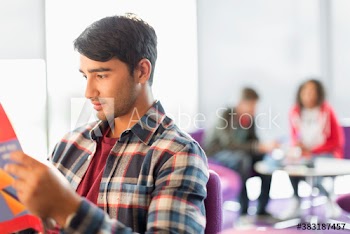 Young male college student studying in student lounge