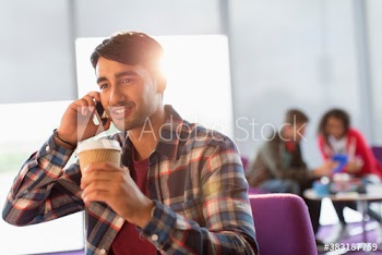 Young male college student with coffee talking on smart phone