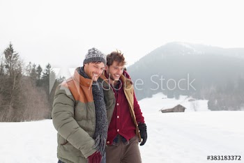 Young male friends walking in snowy field