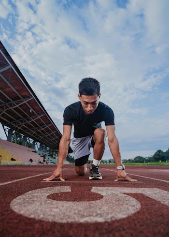 Young Male Sprinter in Starting Position on Track