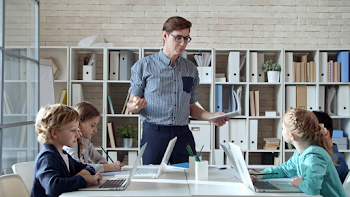 Young male teacher of information technology standing in front of ...