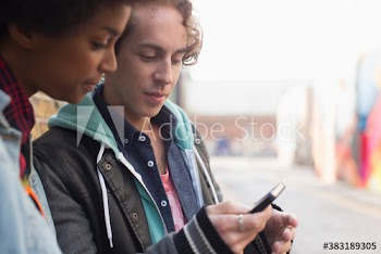 Young man and woman using mobile phone on street