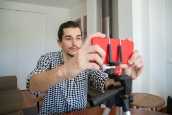 Young Man Filming with Mobile Phone on Tripod