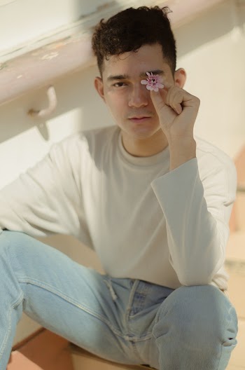 Young Man Holding A Pink Flower Close To Left Eye