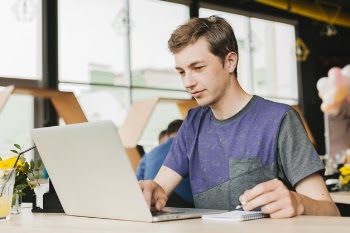 Young man in cafe working on laptop Free Photo