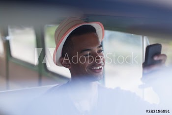 Young man in hat using smart phone in van