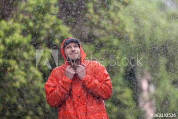 Young man in raincoat walking in rain