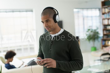 Young man listening to music with headphones and mp3 player at home