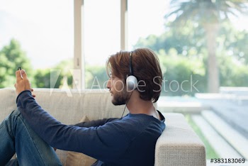 Young man listening to music with headphones and mp3 player on sofa