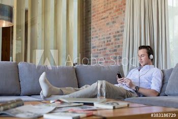Young man listening to music with headphones on sofa