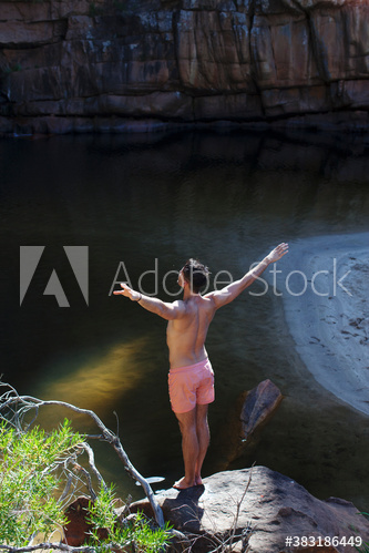 Young man preparing to dive off rocks