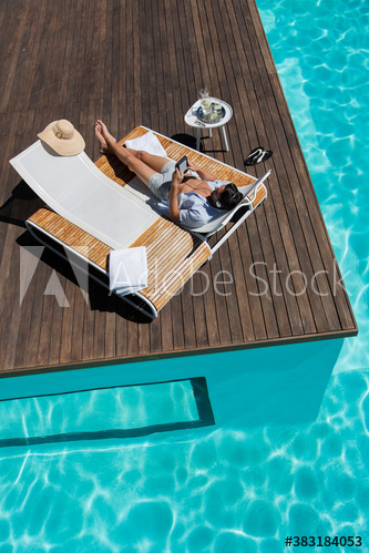 Young man relaxing on lounge chair at sunny summer poolside
