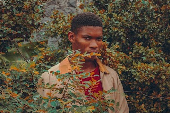 Young Man Standing Behind Plants