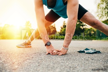 Young man stretching on road during sunset