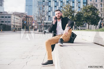 Young man talking on smartphone while sitting outdoors