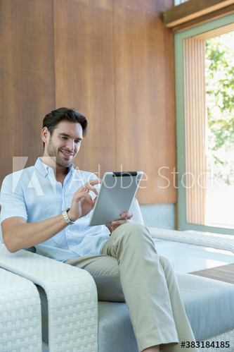 Young man using digital tablet in armchair