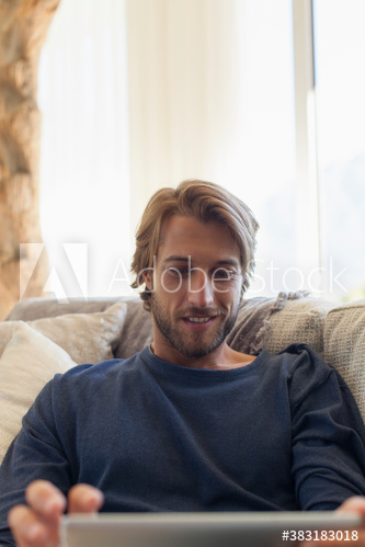 Young man using digital tablet on sofa