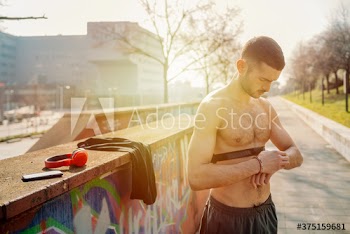 Young man using fitness tracker while standing on street