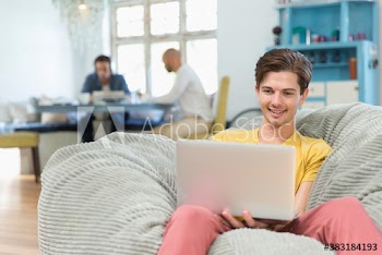 Young man using laptop in beanbag chair