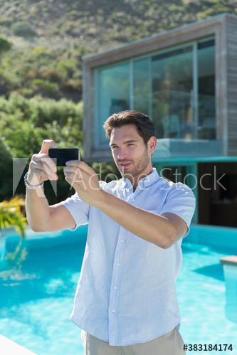 Young man using smart phone at sunny poolside