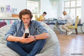Young man using smart phone in beanbag chair