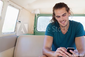 Young man using smart phone inside van