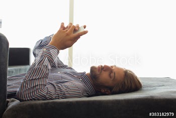 Young man using smart phone on ottoman