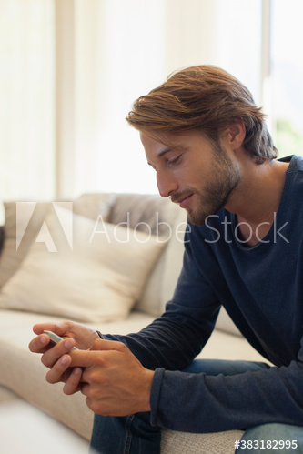 Young man using smart phone on sofa