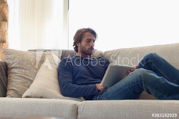 Young man with digital tablet relaxing on sofa