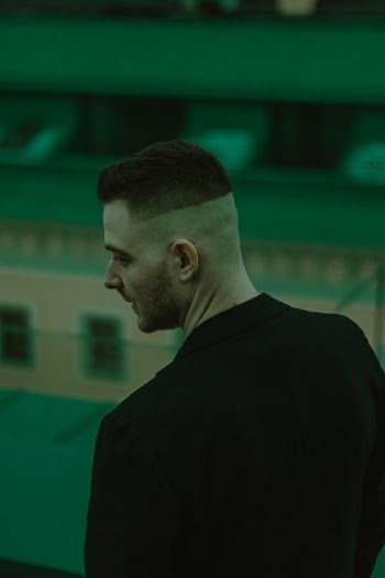 Young Man with Half Shaved Head Standing Backwards · Free Stock Photo