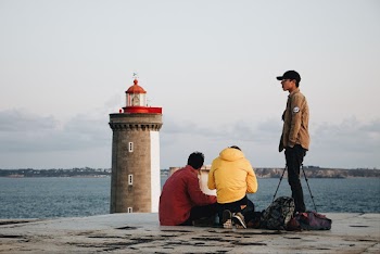 Young Men On The Concrete Pavement  By The Sea Close To The Lighthouse