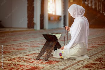 Young muslim woman praying in mosque with quran
