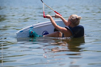 Young pretty slim woman riding wakeboard in summer