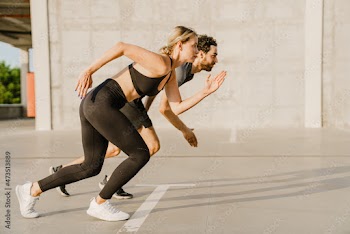 Young runners doing exercise while working out together on parking