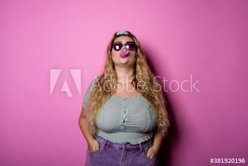 Young woman blowing bubble gum while standing indoors