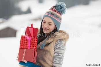 Young woman carrying Christmas gifts in snow