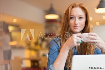 Young woman drinking coffee and working at laptop in cafe