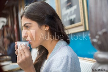 Young woman drinking espresso at sidewalk cafe