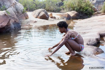 Young woman in bikini on rock at stream