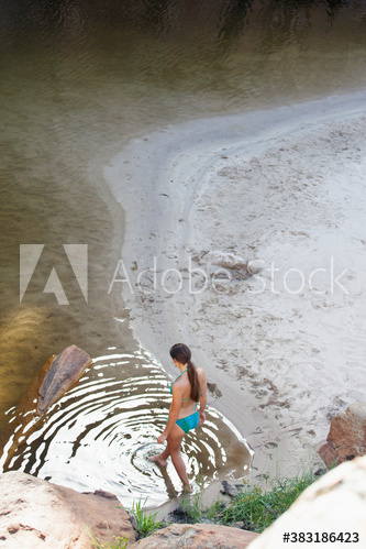 Young woman in bikini stepping into lake