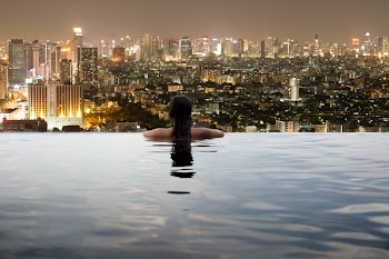 Young woman in outdoor swimming pool with city view at night