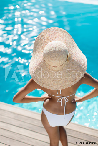 Young woman in sun hat and bikini at sunny poolside