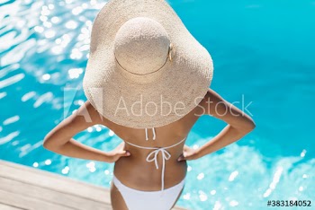 Young woman in sun hat and bikini at sunny poolside