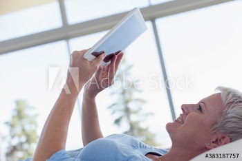 Young woman laying and using digital tablet
