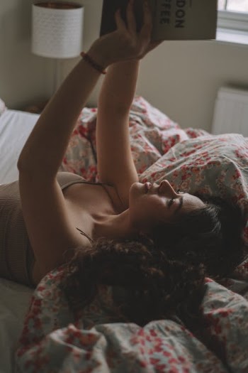 Young Woman Laying in Bed and Holding Book over Head · Free Stock Photo