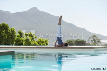 Young woman practicing yoga supported shoulderstand at sunny poolside