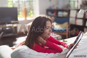 Young woman reading magazine on sofa