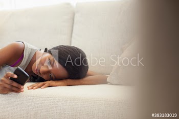 Young woman relaxing on sofa with smart phone