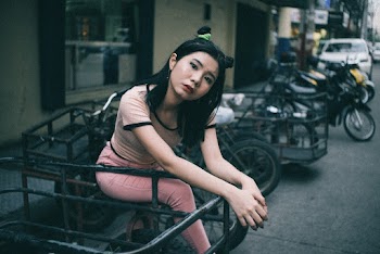 Young Woman Sitting On A Parked Motorcycle On The Side Of The Street