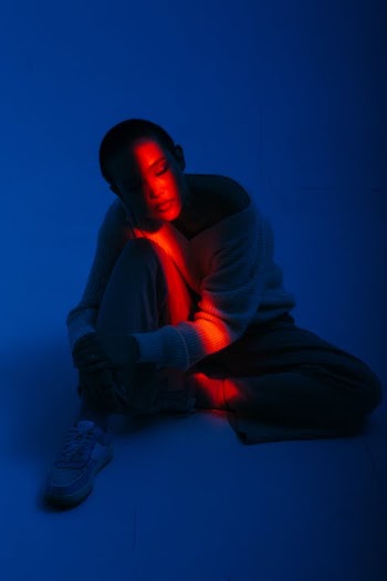 Young Woman Sitting on Floor in Stripe of Red Light in Dark Room  · Free Stock Photo